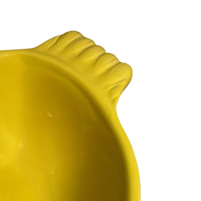 Close-up detail of a bright yellow molded bowl, showing a ribbed textured edge against a plain white background.