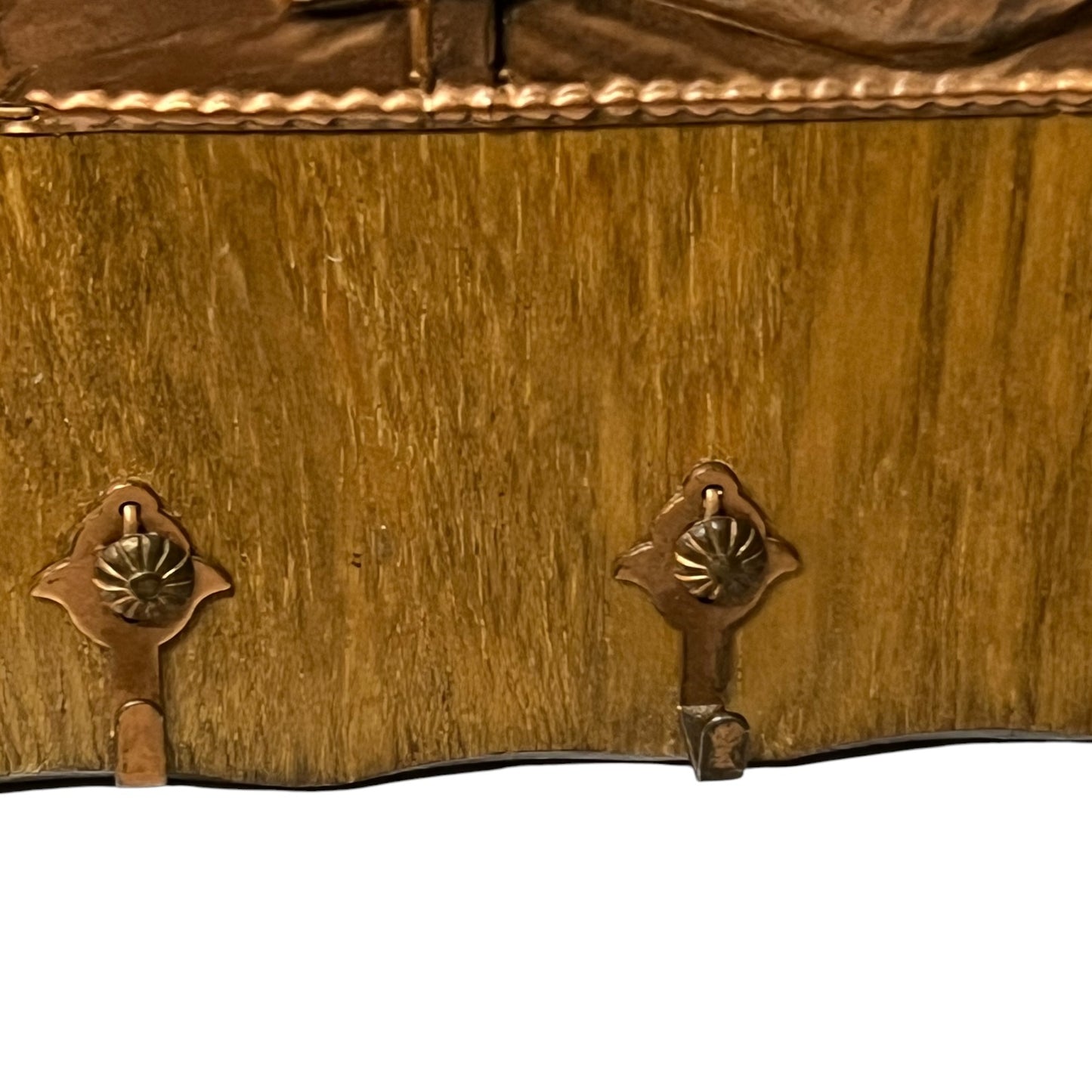 Close-up of a wooden and copper key holder against a white background.