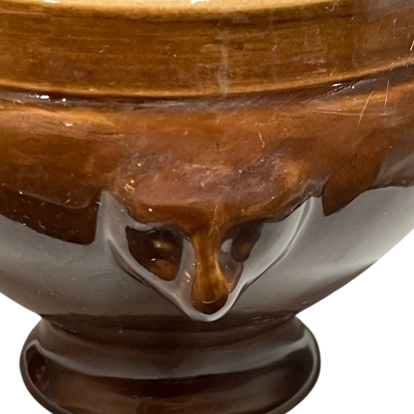 Brown ceramic bowl with decorative lion head handles on a white background