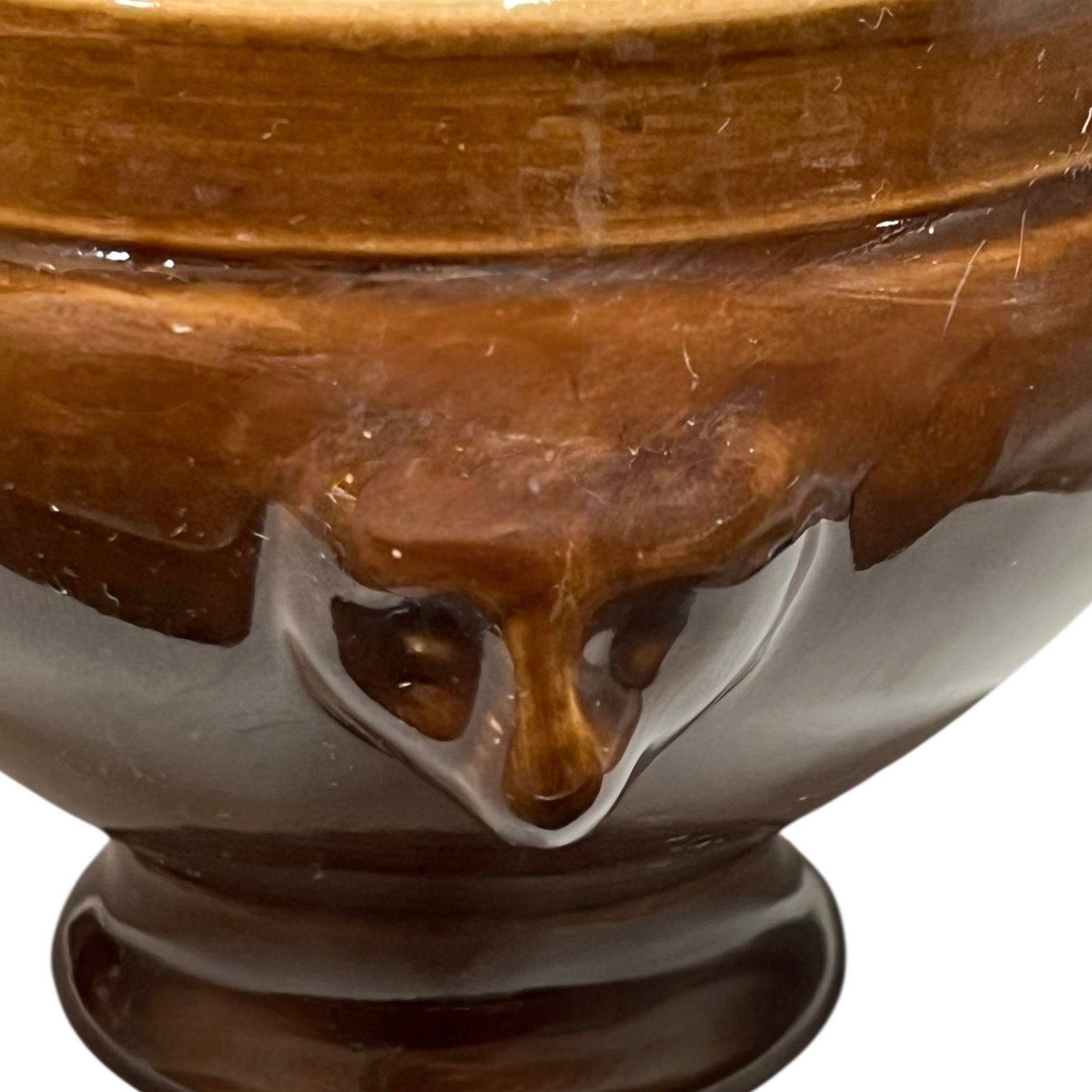 Brown ceramic bowl with decorative lion head handles on a white background