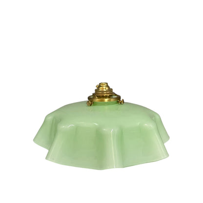 pale green milk glass lampshade with brass fittings on a white background