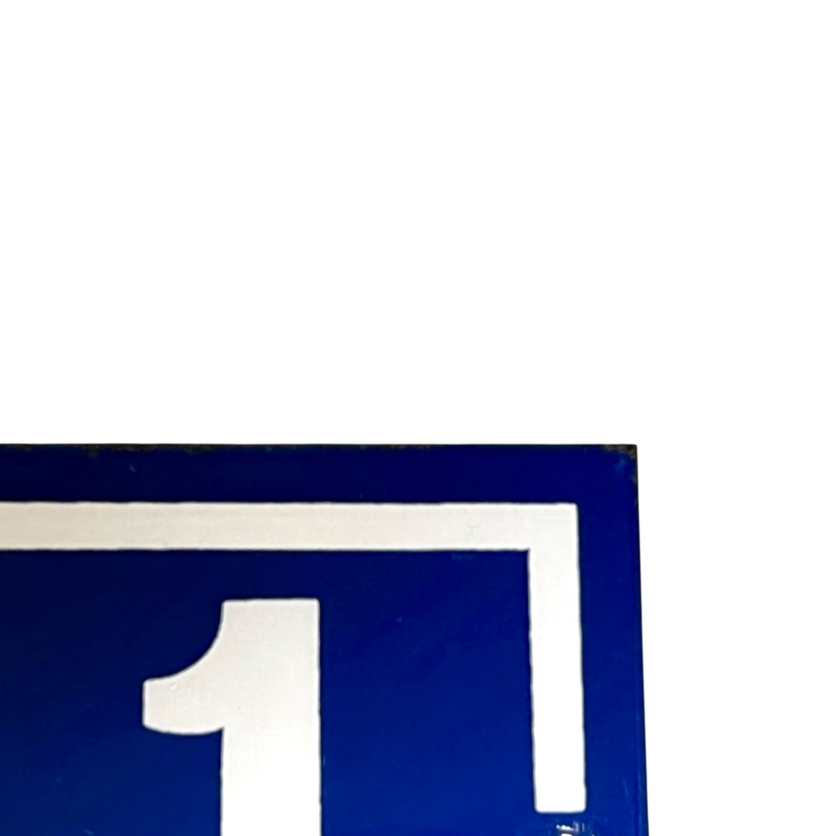 A close-up of a blue and white sign showing the number 1 inside a square border, cropped on the left and bottom edges against a white background.