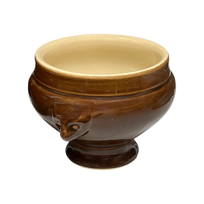 Brown ceramic bowl with decorative lion head handles on a white background