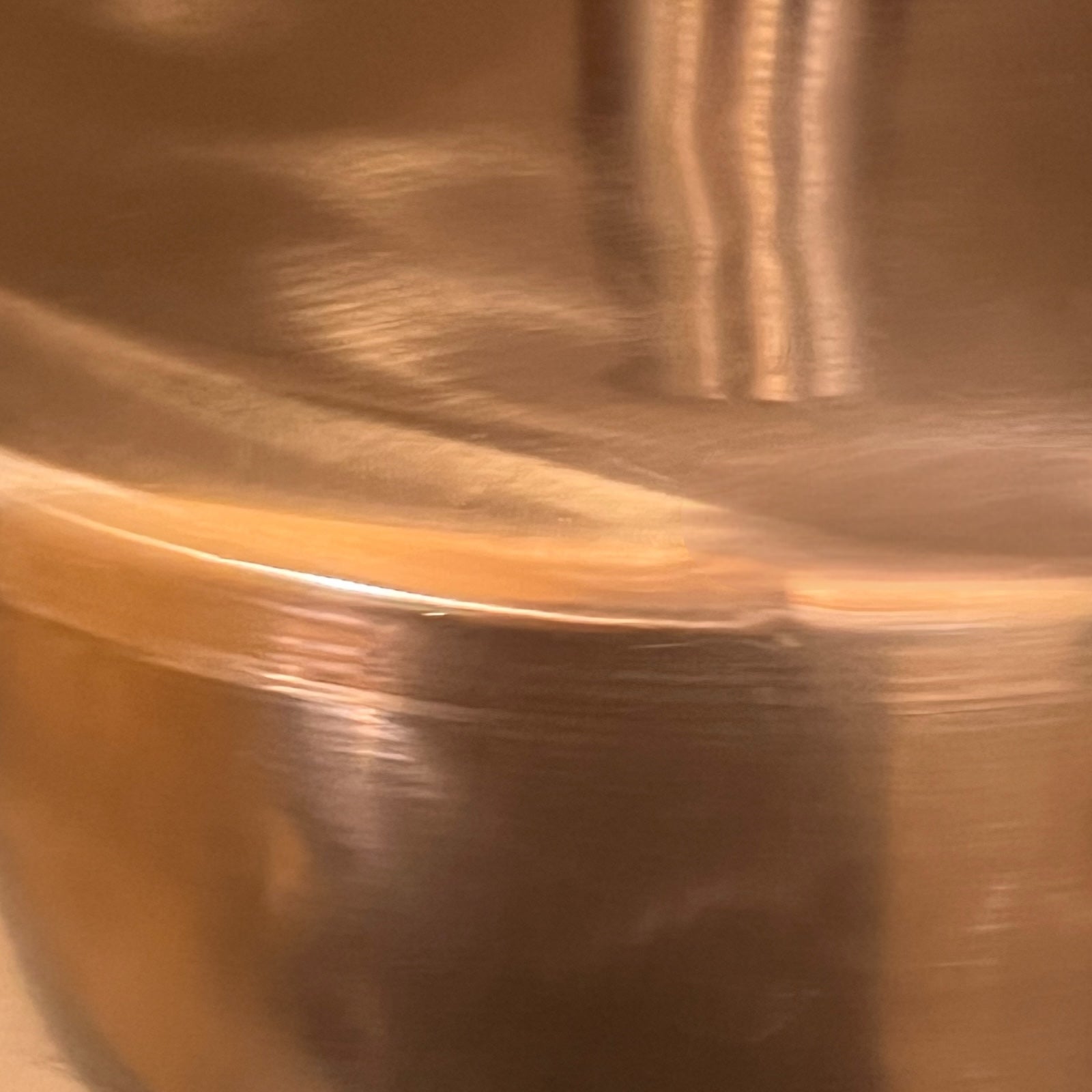 Close-up of a copper sink with a brass handle on a white background