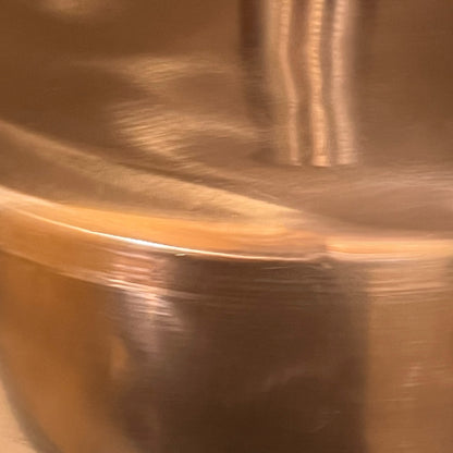 Close-up of a copper sink with a brass handle on a white background