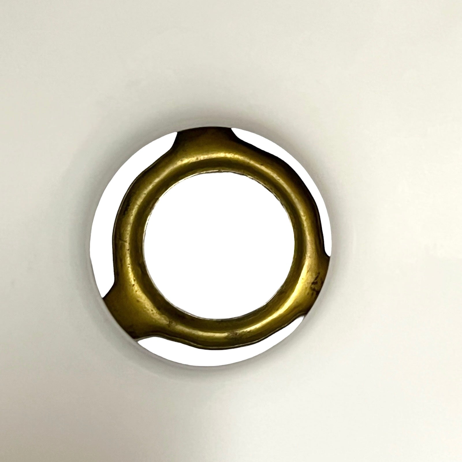 A circular metallic ring-shaped product with a polished gold finish and a white interior, photographed against a plain off-white background.