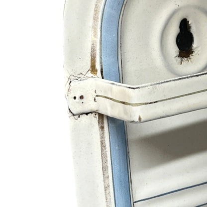 Close-up of a distressed white metal enamel drip tray on a white background