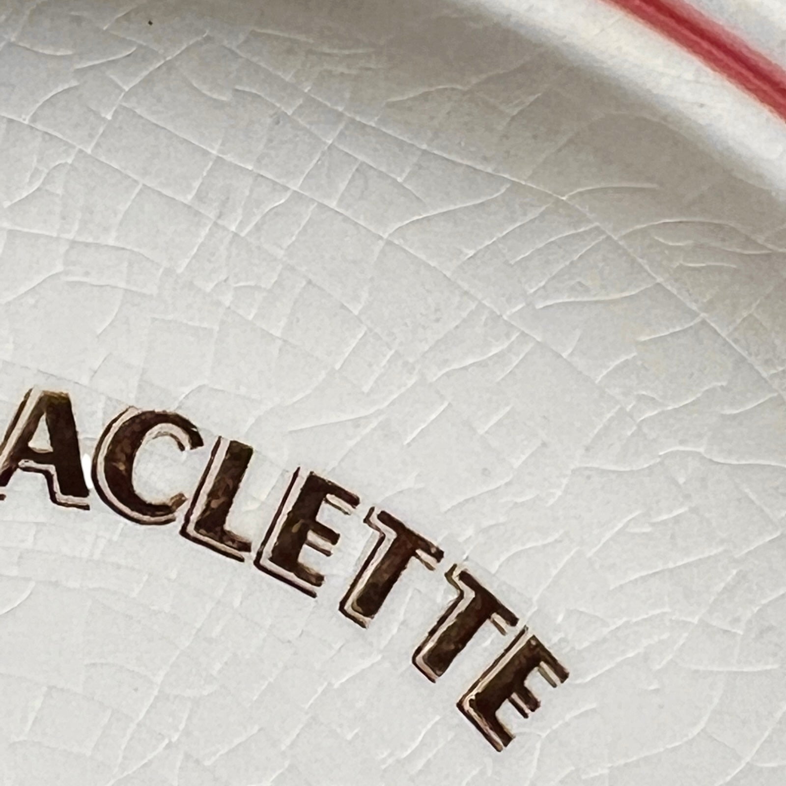 Close-up of a white ceramic dish with 'Raclette' branding.