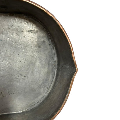 Close up of a copper roasting pan with a long handle on a white background