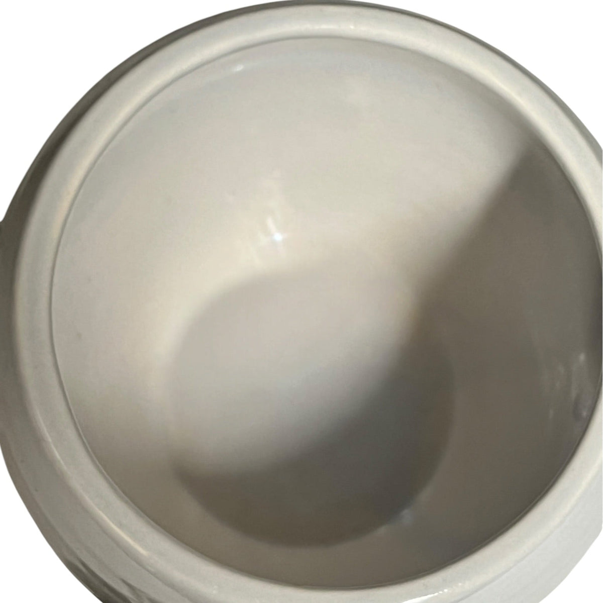 A close-up view of a glossy white ceramic bowl or cup interior, showing a smooth glazed surface with soft reflections and shadows.