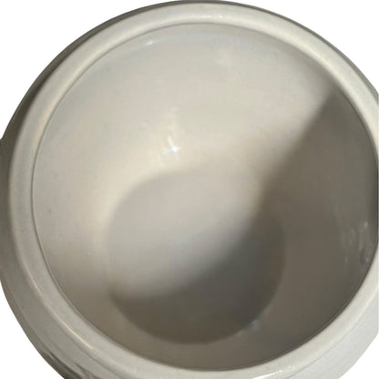 A close-up view of a glossy white ceramic bowl or cup interior, showing a smooth glazed surface with soft reflections and shadows.
