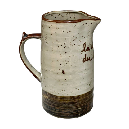 Ceramic speckled brown and cream vase with French text on a white background