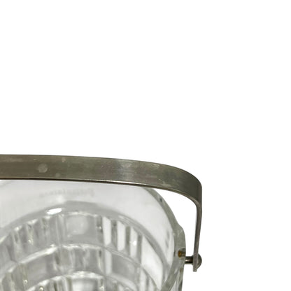 Close-up of a clear glass container or bucket with a curved metal handle and rim, shown against a plain white background.