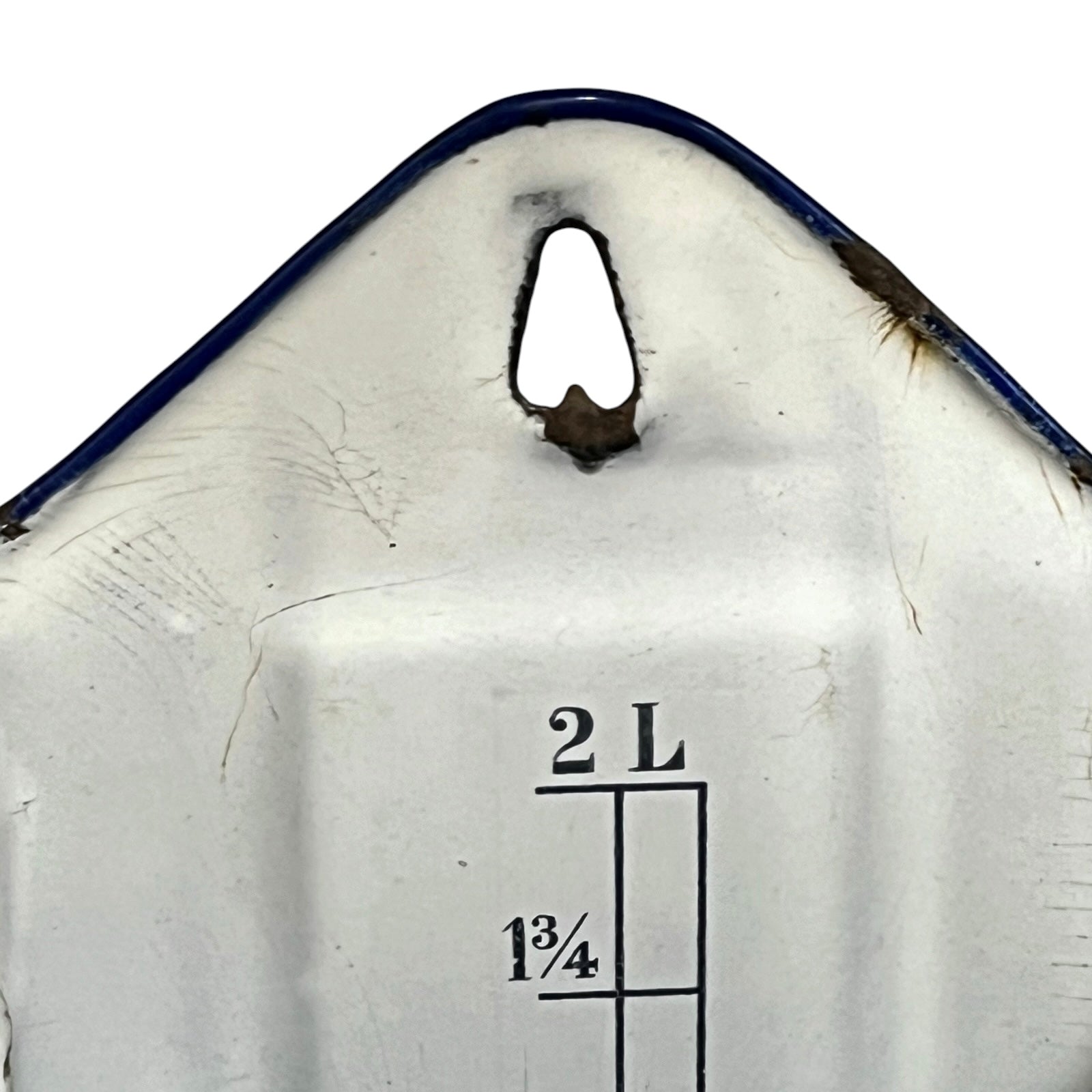 Close-up of the back of a white enamel water jug with a blue rim, showing a hanging hole, scuffs, and printed markings including '2 L' and '1 3/4'.