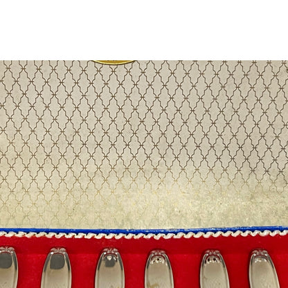Close-up of a red and blue box containing 12 French dessert forks on a white background