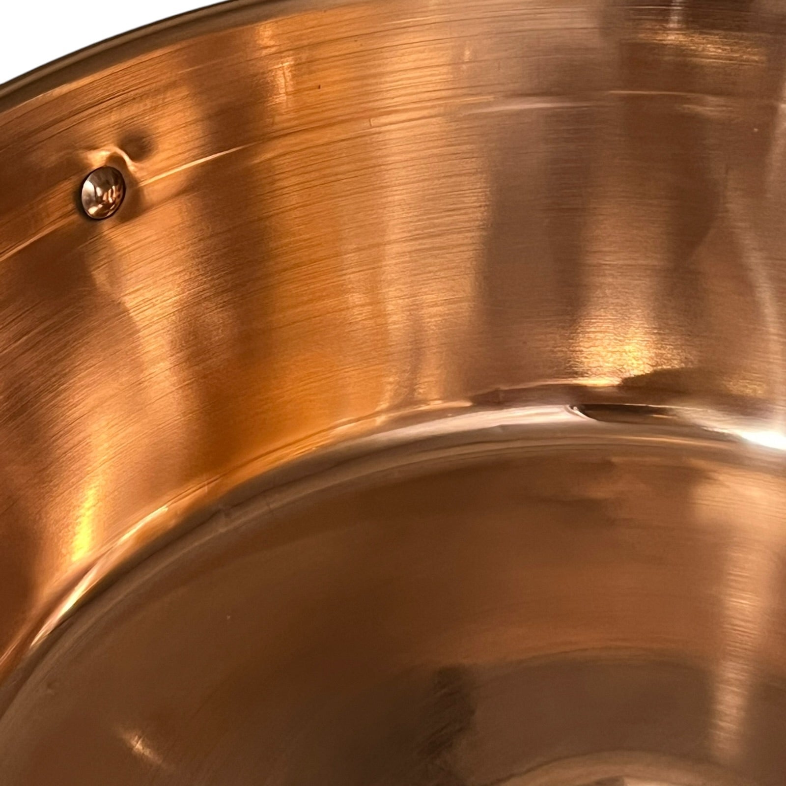 Close-up of a copper sink with a drain and stopper.