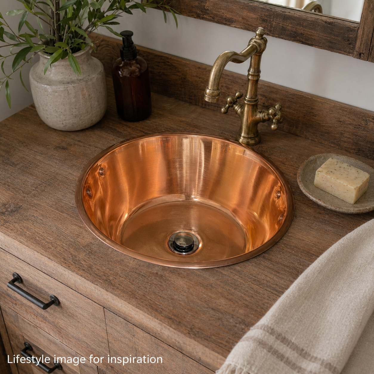 Up cycled French copper sink with handles ideal for a rustic bathroom, vanity or camper van sink on a wooden vanity with a vintage-style faucet.
