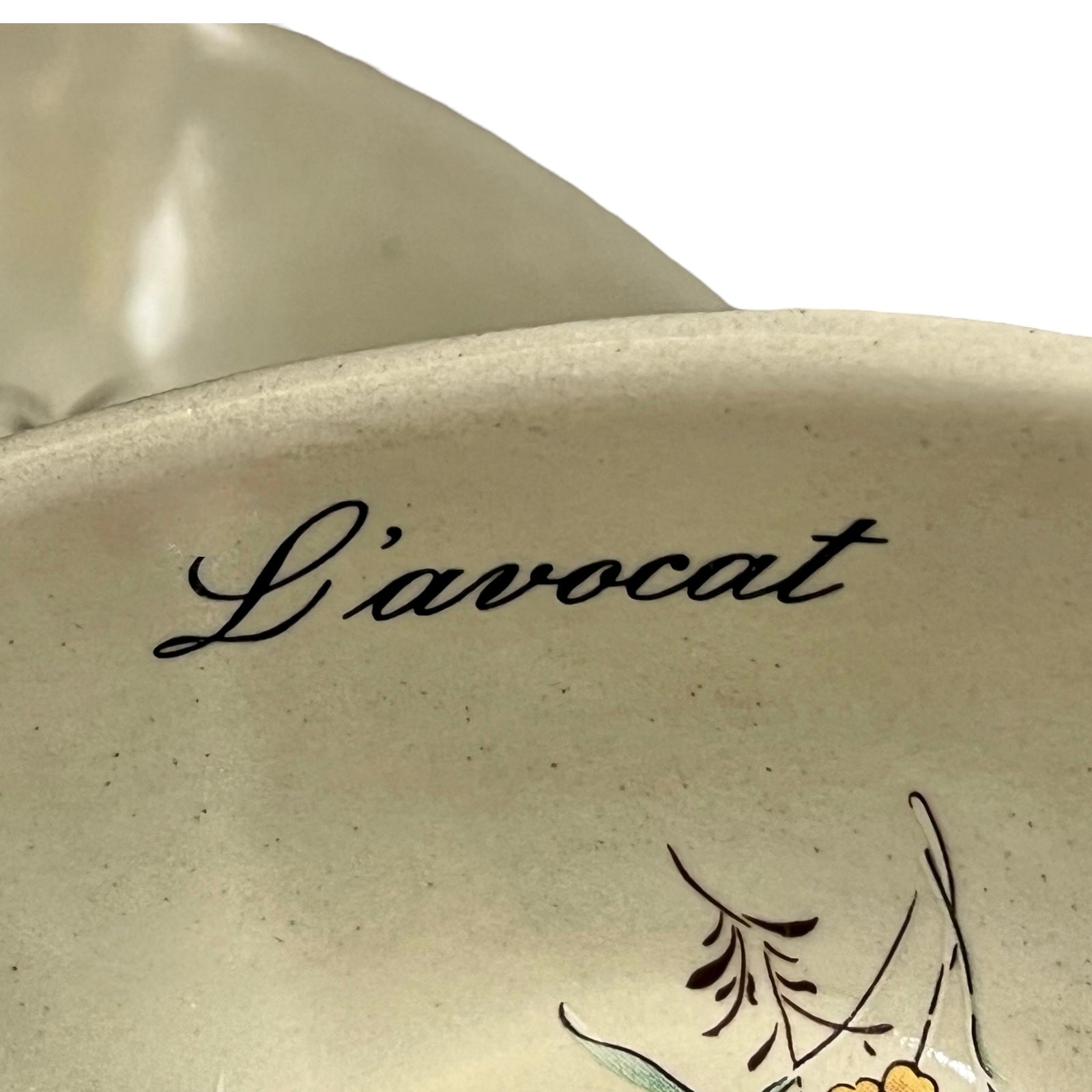 Beige ceramic dish with floral design and 'L'avocat' text on a white background