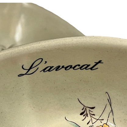 Beige ceramic dish with floral design and 'L'avocat' text on a white background