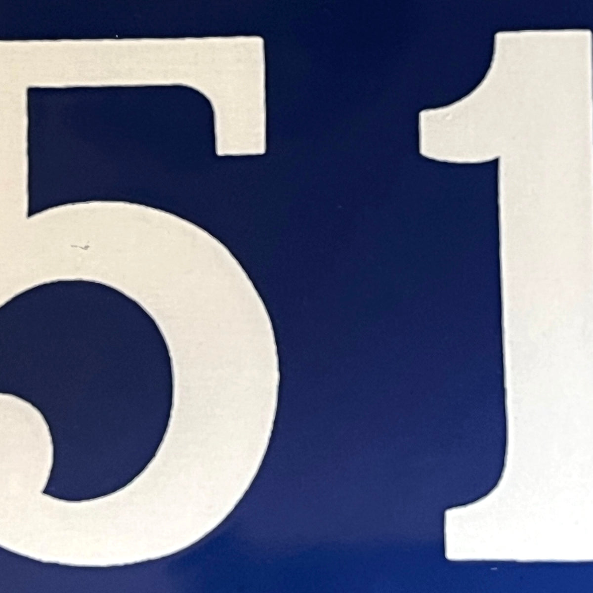 A close-up of large white numerals, showing the digits 5 and 1 on a dark blue background.