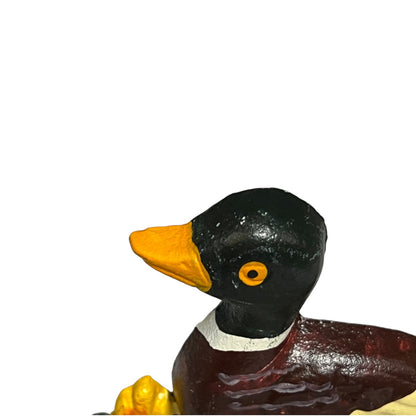 A close-up of a painted duck door stop on a plain white background. The duck has a glossy black head, yellow beak and eye, a white collar, and a dark reddish-brown body.