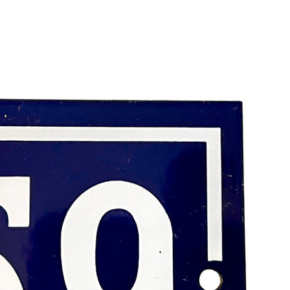 Close-up of a dark blue rectangular sign or plaque with large white numerals and a white border, shown against a white background.