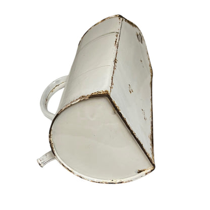 A vintage-style white enamel metal pitcher with a distressed, chipped finish showing brown rust-like detailing along the seams and edges, isolated on a white background.