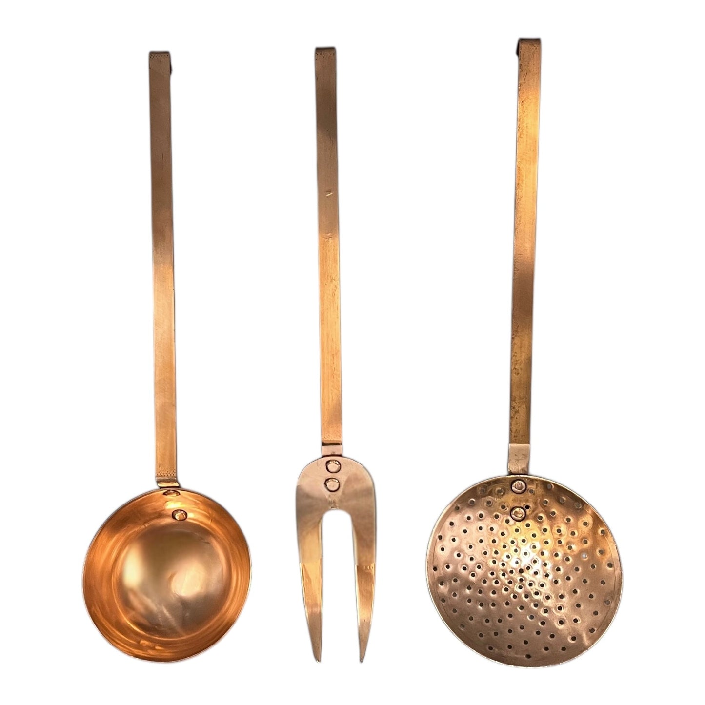 Set of three solid copper kitchen utensils on a white background