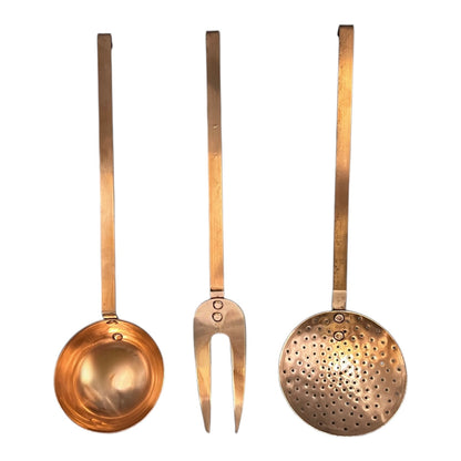 Set of three solid copper kitchen utensils on a white background