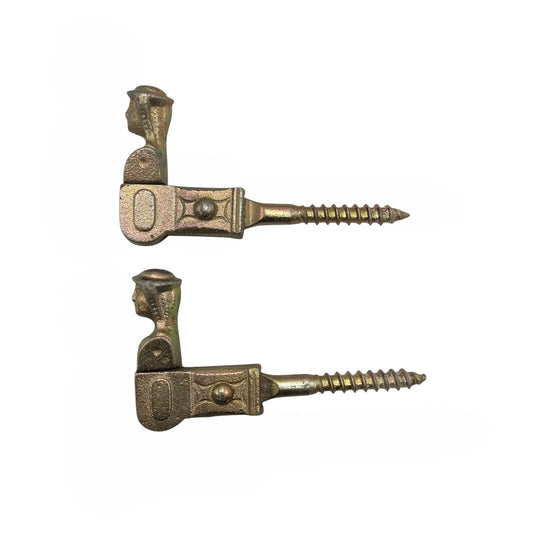 Two brass coloured French decorative shutter catches on a white background