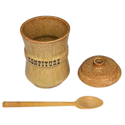 Ceramic confiture jar with wooden spoon on a white background