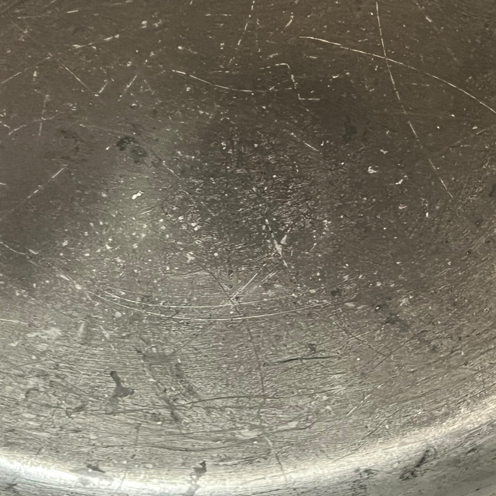 Close up of the inside of a French copper pan with tin lining on a white background