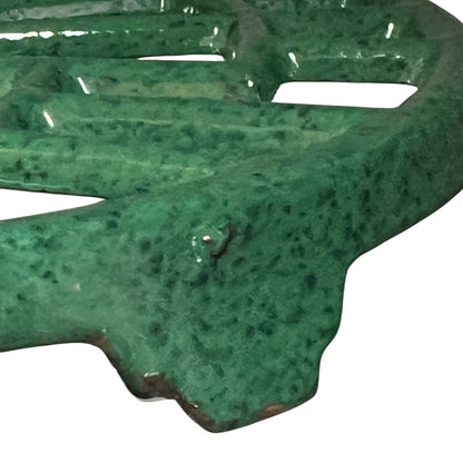 Close up of a green vintage French cast iron enamelled pan trivet on a white background