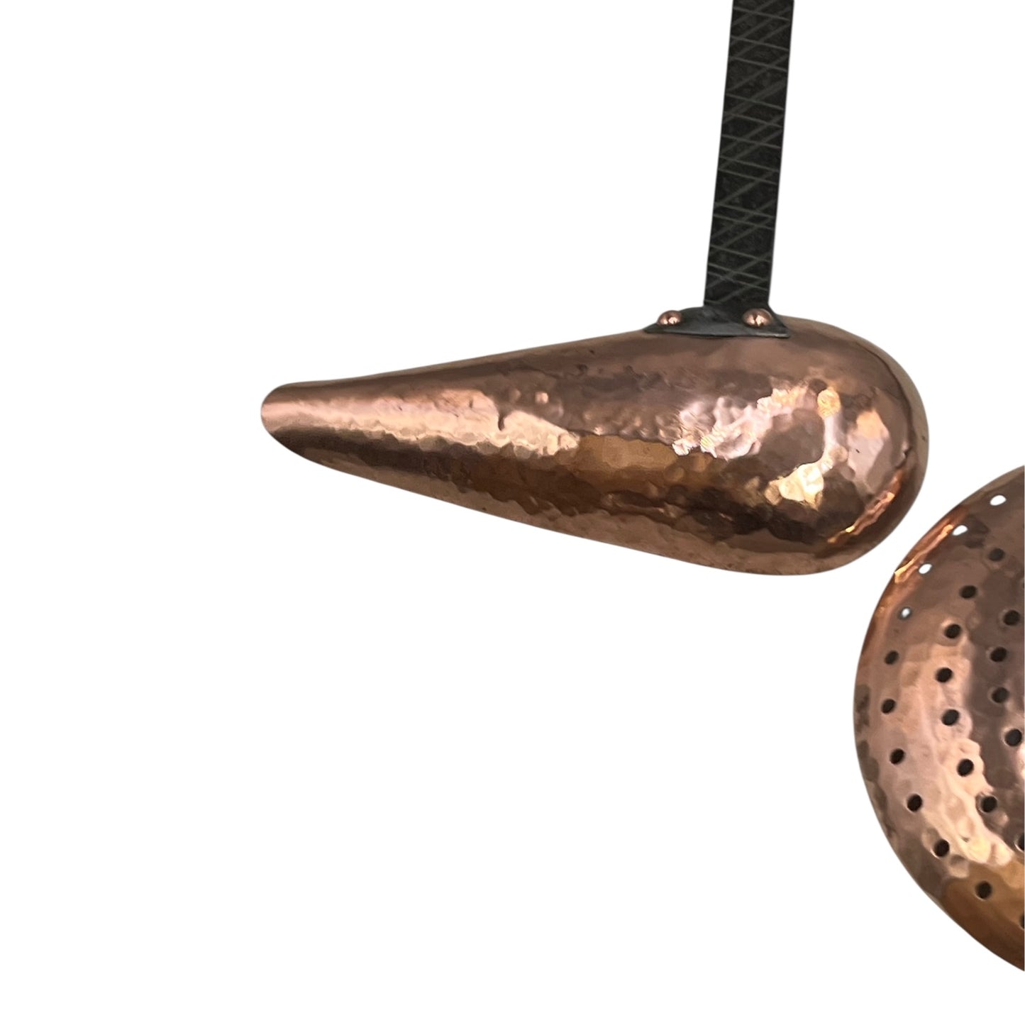 Close up of French copper kitchen utensils with black handles on a white background