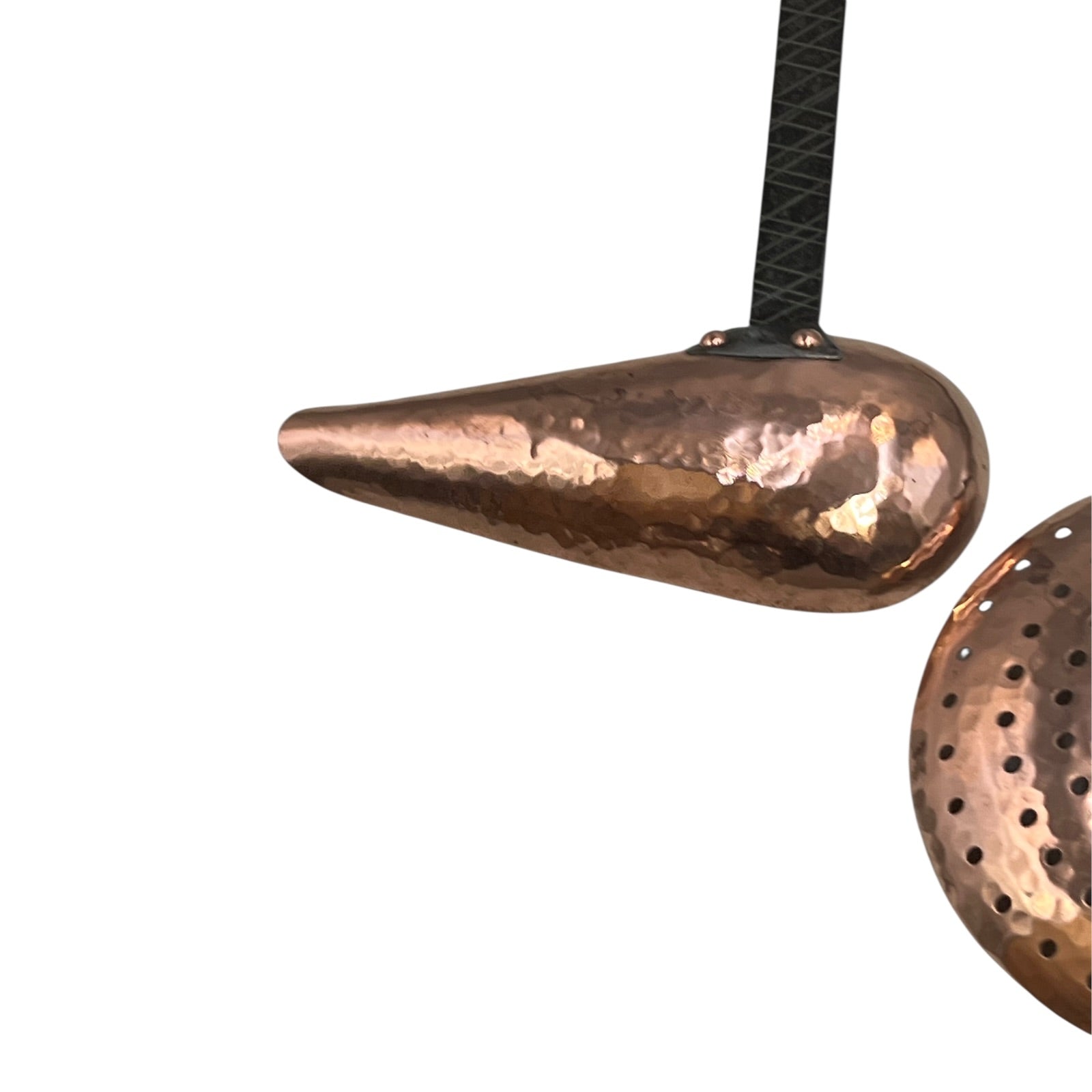 Close up of French copper kitchen utensils with black handles on a white background