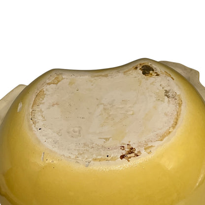 Close-up of the bottom of a yellow ceramic bowl or dish, showing a glossy glazed interior surface with some discoloration and minor staining.