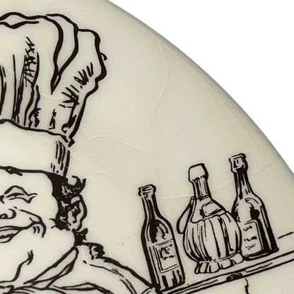 Decorative plate with black line art of a chef, bottles, and a face on a white background