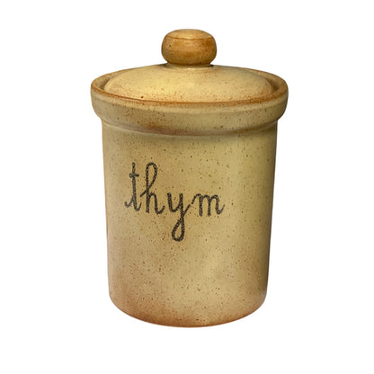 A small speckled ceramic canister with a matching lid and knob, featuring the word 'thym' written in black cursive on the front, set against a plain white background.