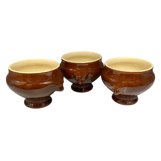 Three brown ceramic bowls with beige interior on a white background
