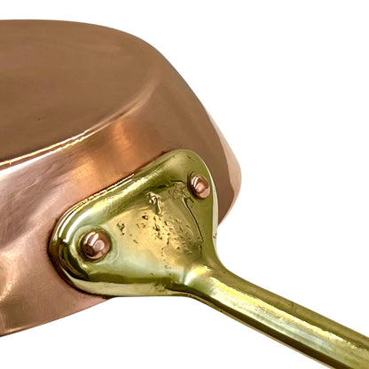 Close-up of a copper saucepan with a brass handle on a white background