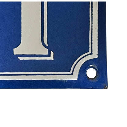 Close up of a blue French metal house number plate with white numbers '111' on a white background