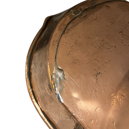 Close up of a copper roasting pan with a long handle on a white background