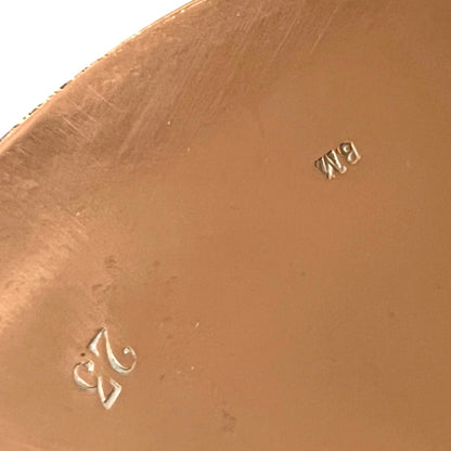 Close up of authentic vintage French copper pan lid showing the number 23 and a pair of initials  on a white background