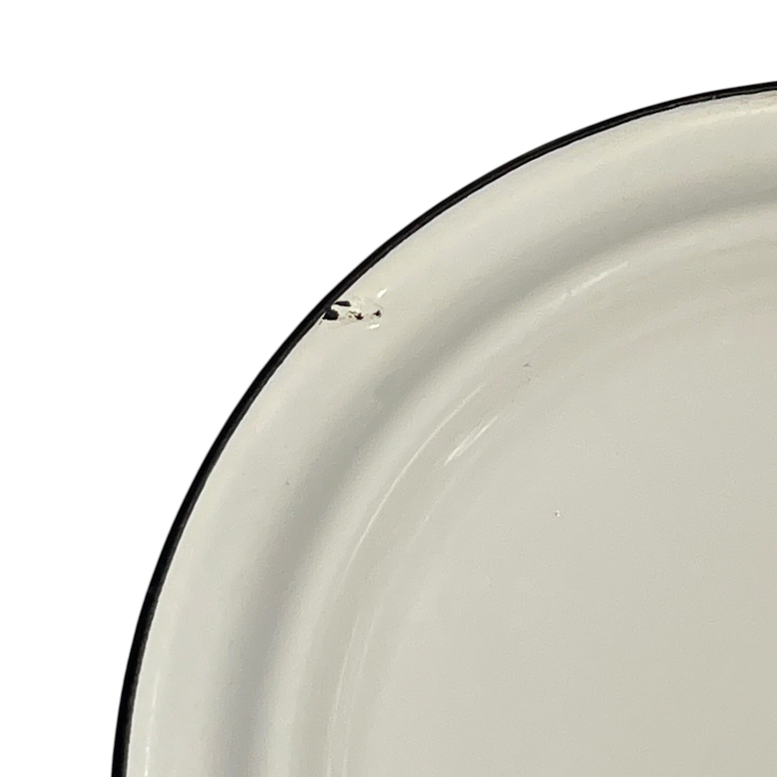 Close-up of a white enamel plate with a thin black rim, showing a small chip on the edge against a white background.