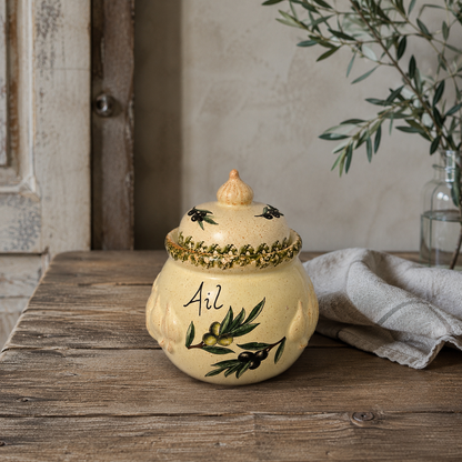 Decorative ceramic jar with lid on a wooden surface, featuring olive designs and the word 'Ail', ideal for a farmhouse kitchen 
