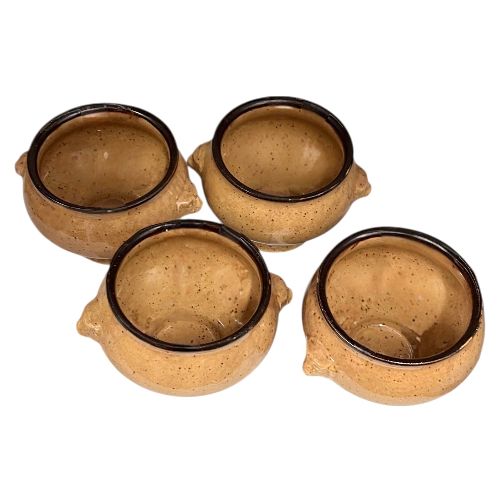 Set of four speckled beige lions head soup bowls with dark rims on a white background