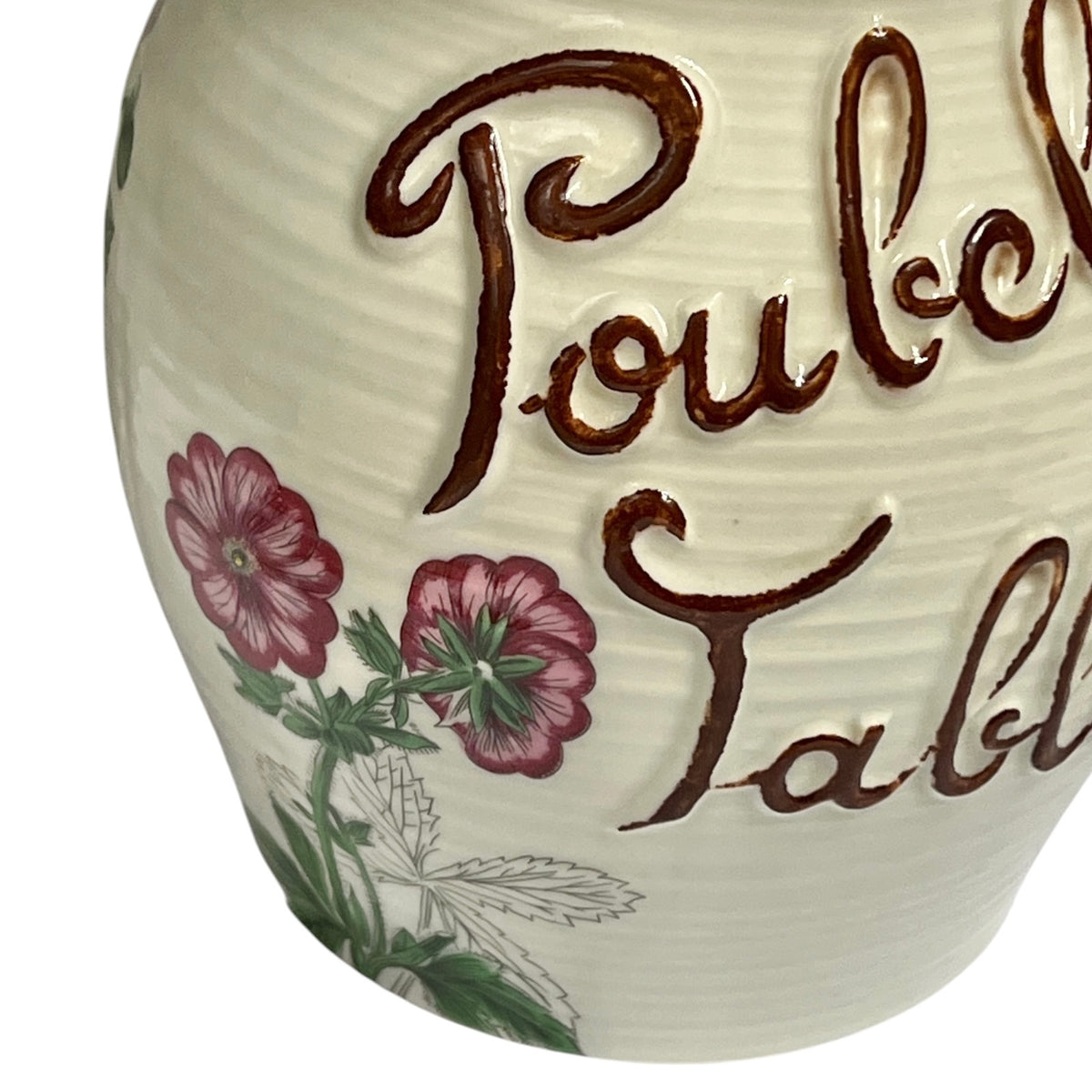 Close-up of a white ribbed ceramic table bin with raised brown script reading 'Poubelle de Table' and pink floral illustrations with green leaves.