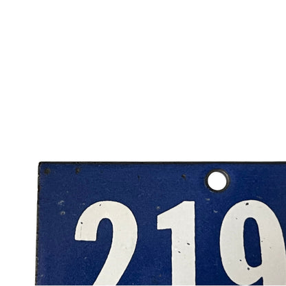 A close-up of a blue rectangular metal plate with large white numerals '2194' and a circular mounting hole near the top right, shown against a white background.