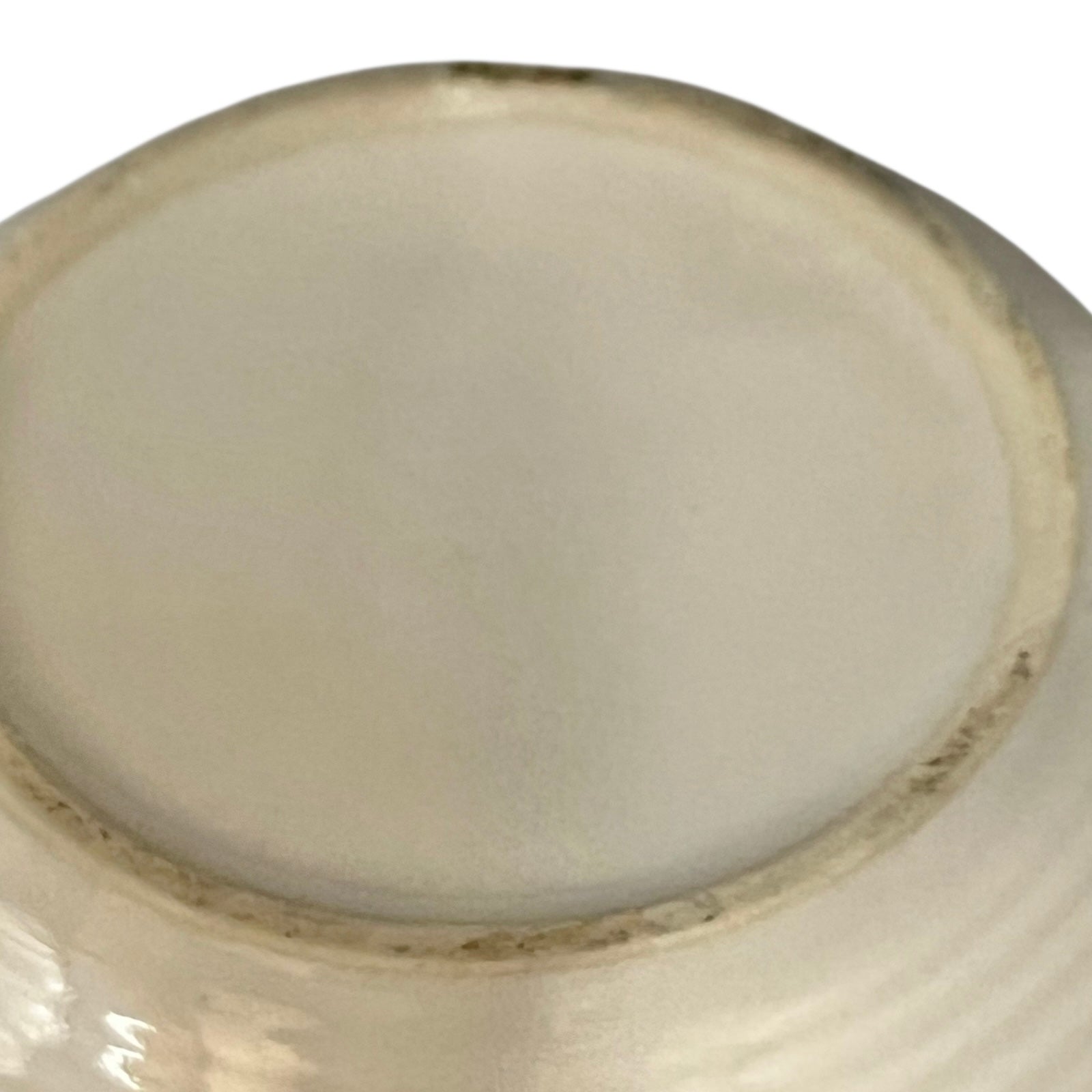 Close-up of a ceramic bowl base with a smooth, light-coloured glaze on a white background