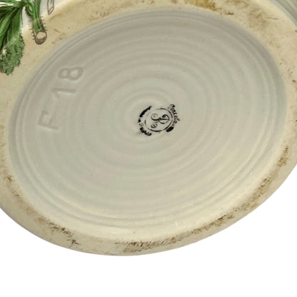 Close-up of the bottom of a round ceramic pot, showing a light beige glazed interior with concentric ring texture, embossed 'F18' text, a small central maker's mark, and a rougher unglazed rim.